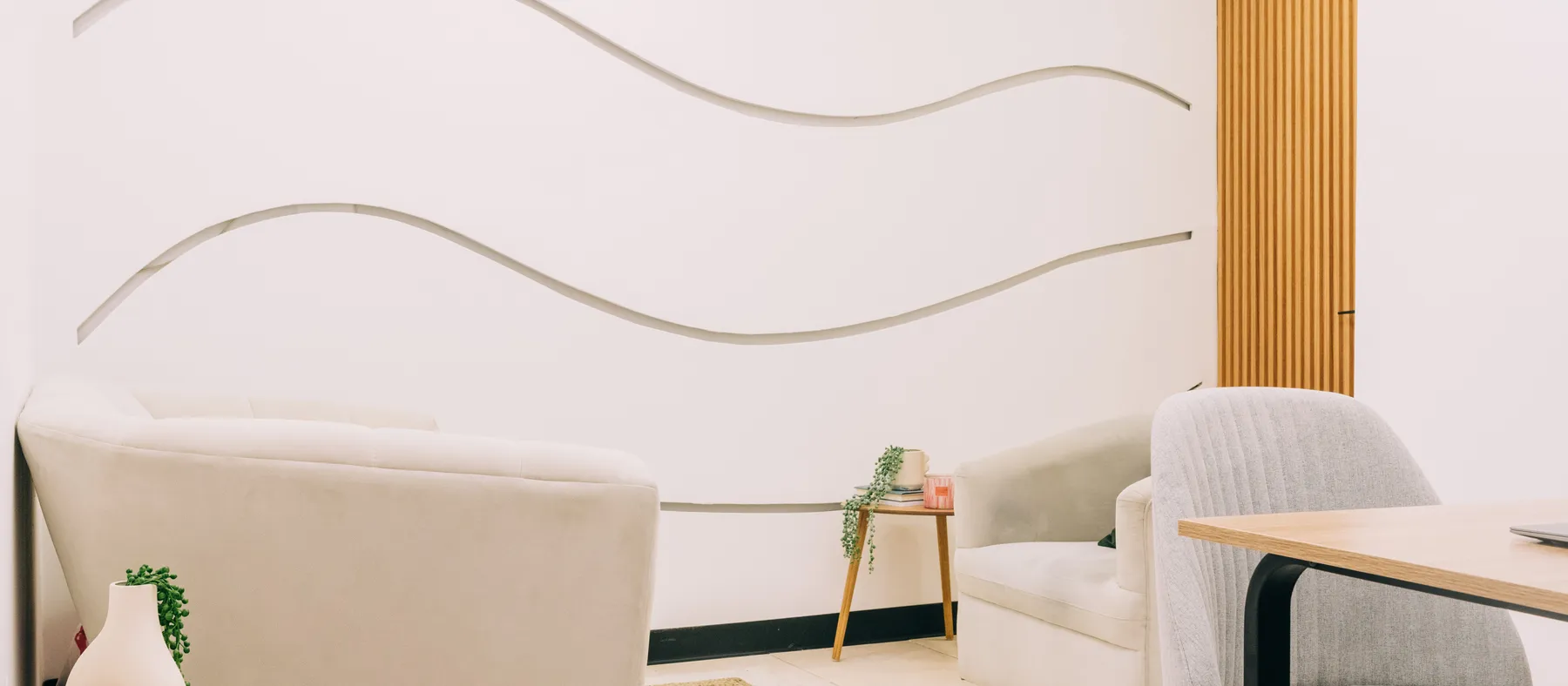 Sala de Mood Clinic en San Salvador: sofás claros, planta y la pared de ondas
