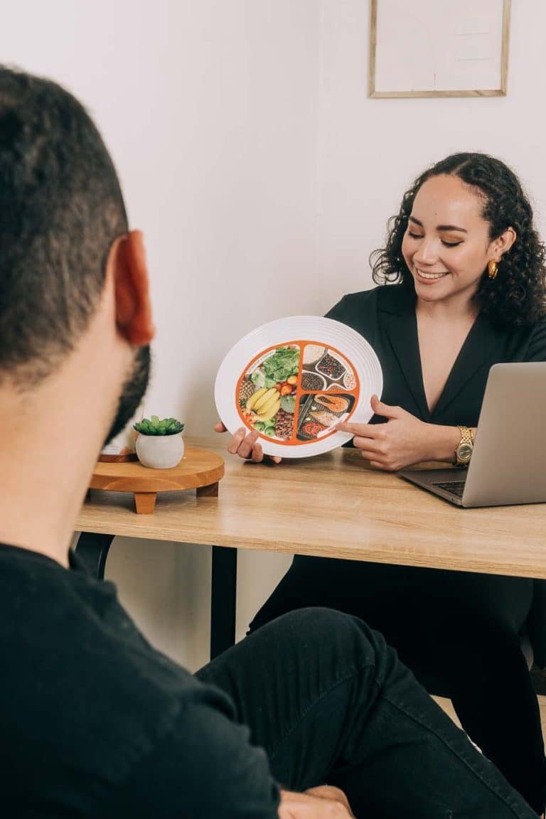 Nutricionista en El Salvador explicando un plato balanceado a un paciente durante una consulta nutricional.