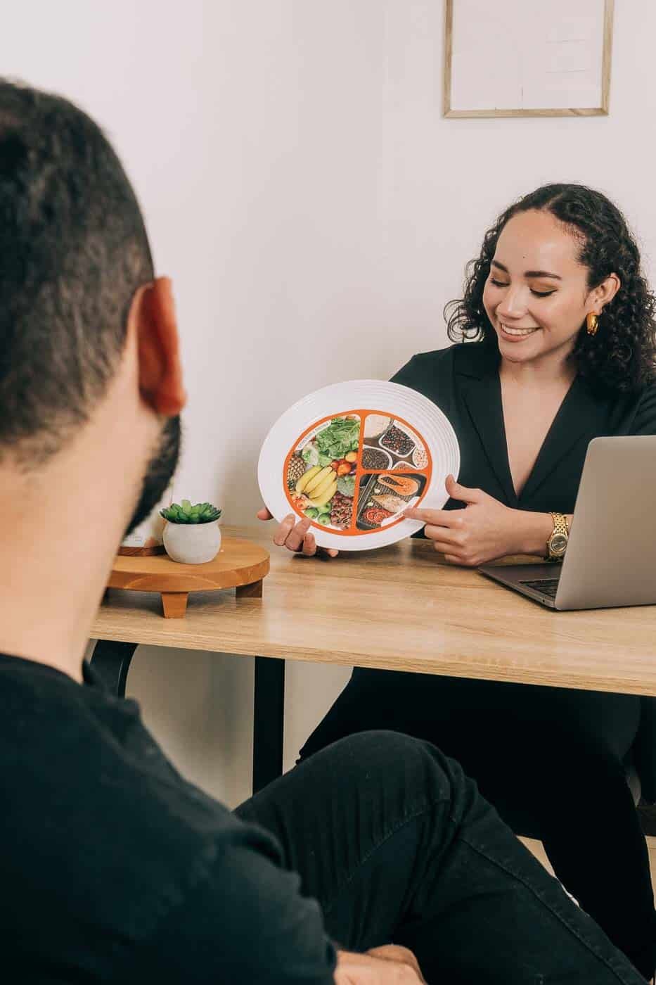 Nutricionista en El Salvador explicando un plato balanceado a un paciente durante una consulta nutricional.
