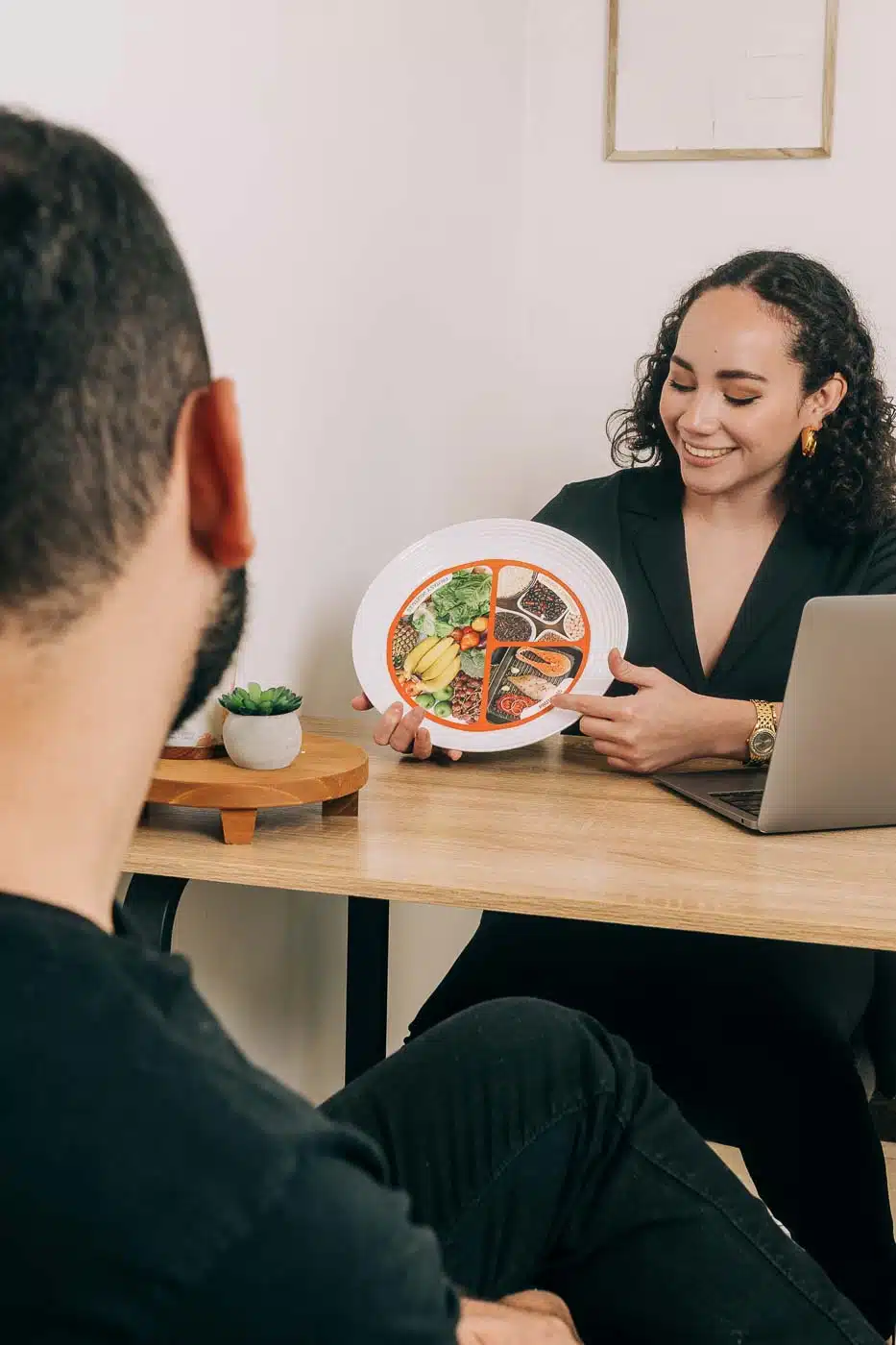 Nutricionista en El Salvador explicando un plato balanceado a un paciente durante una consulta nutricional.
