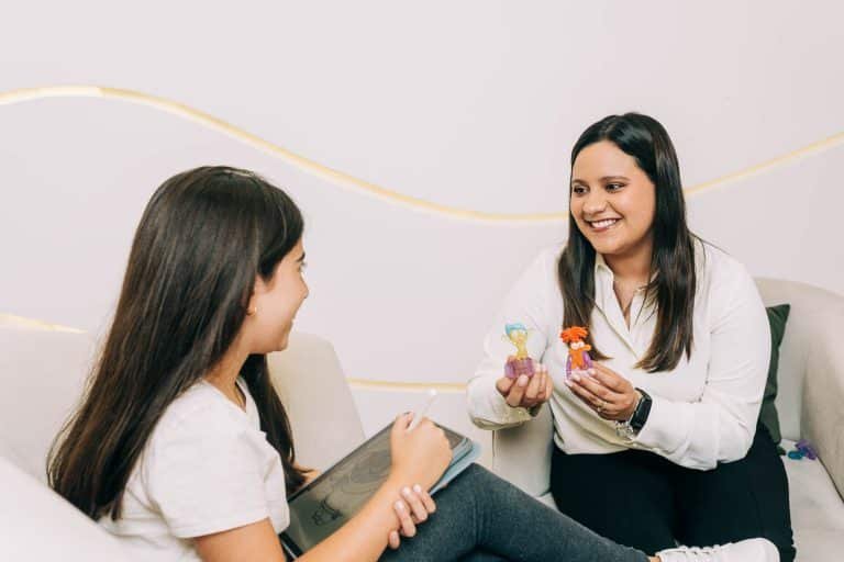 Psicóloga trabajando en terapia para niños en El Salvador, utilizando figuras de personajes animados y una tablet