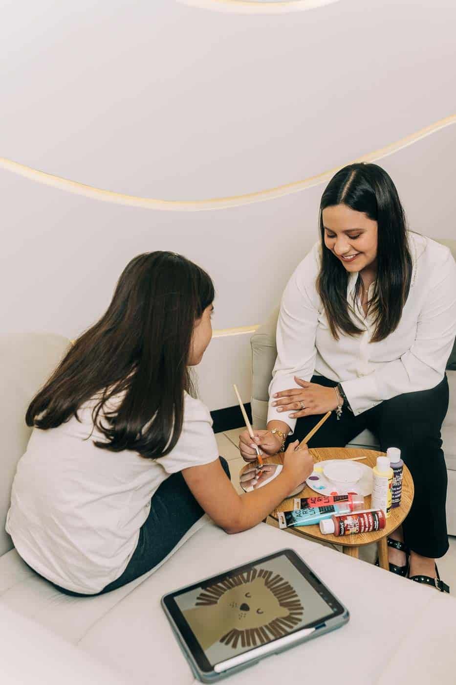 Psicóloga trabajando en terapia con una niña utilizando pintura y actividades creativas.